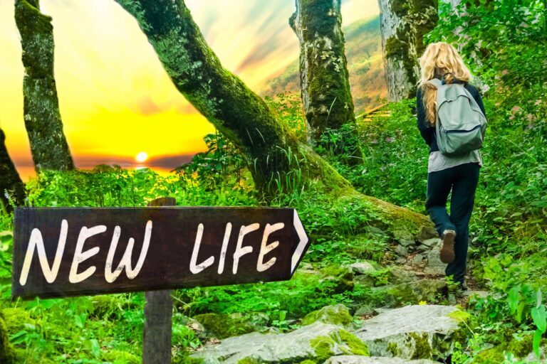 Woman hiking in the woods near a sign reading "NEW LIFE"