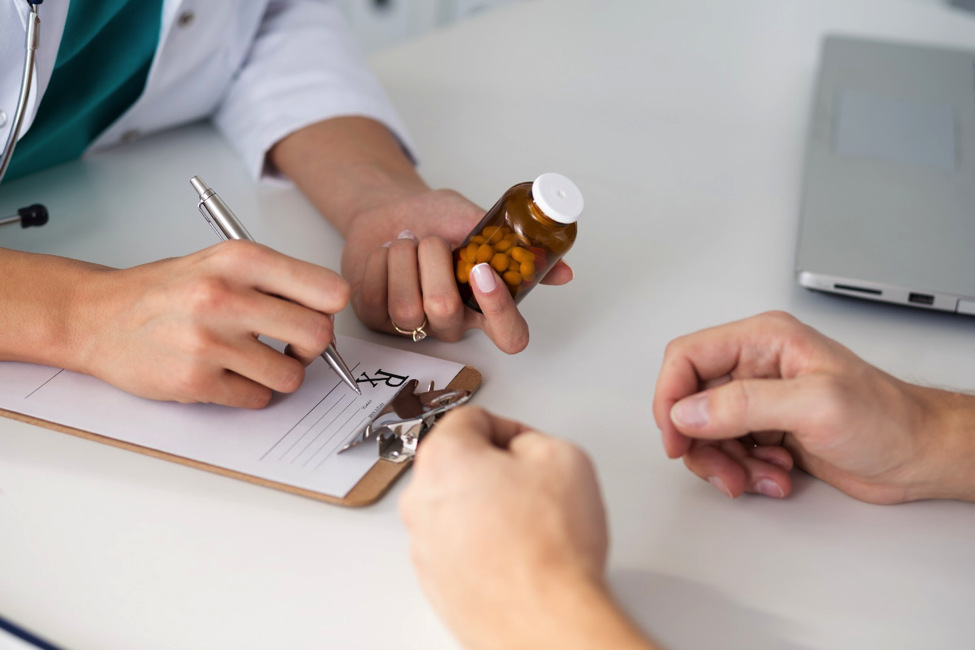 Image of a doctor’s hands holding a pill bottle and filling out a prescription
