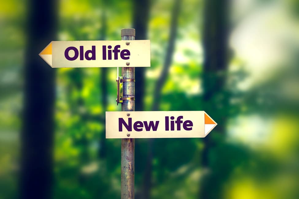 Two signs pointing in opposite directions. Forward sign says “new life,” backward sign says “old life.