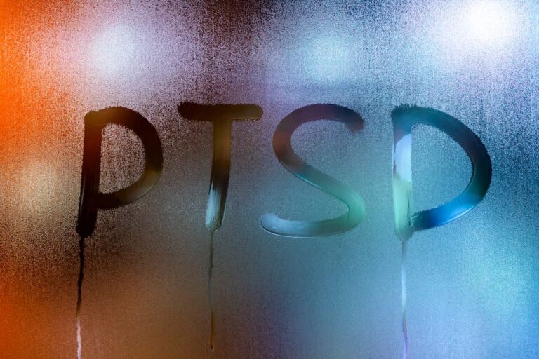 Letters PTSD written on a rainy window at night.