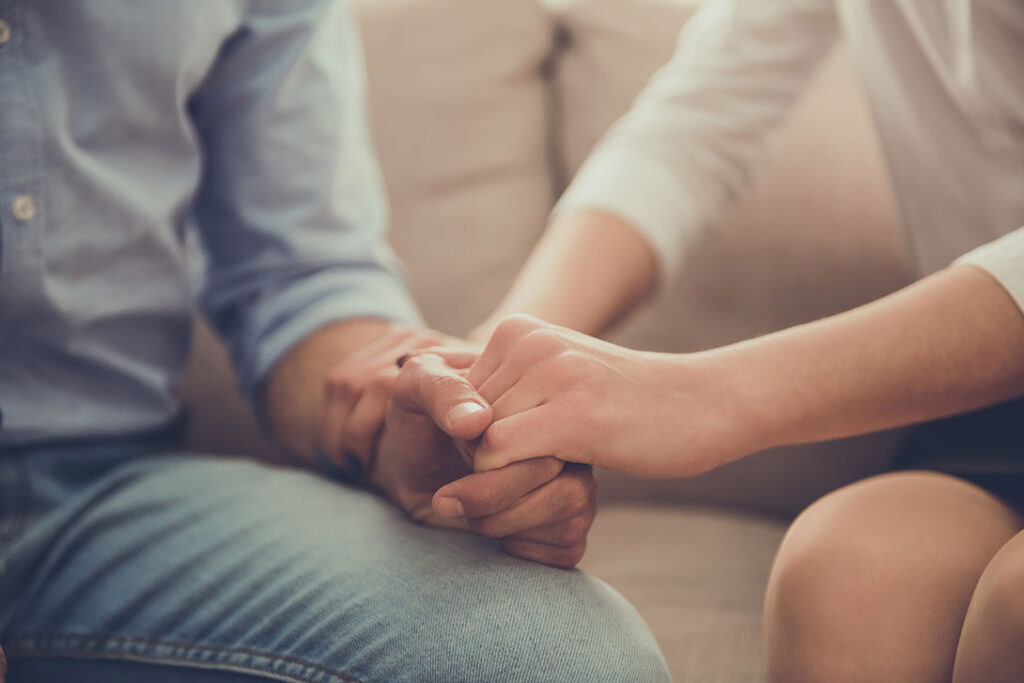 Close up of woman holding a mans hand supportively