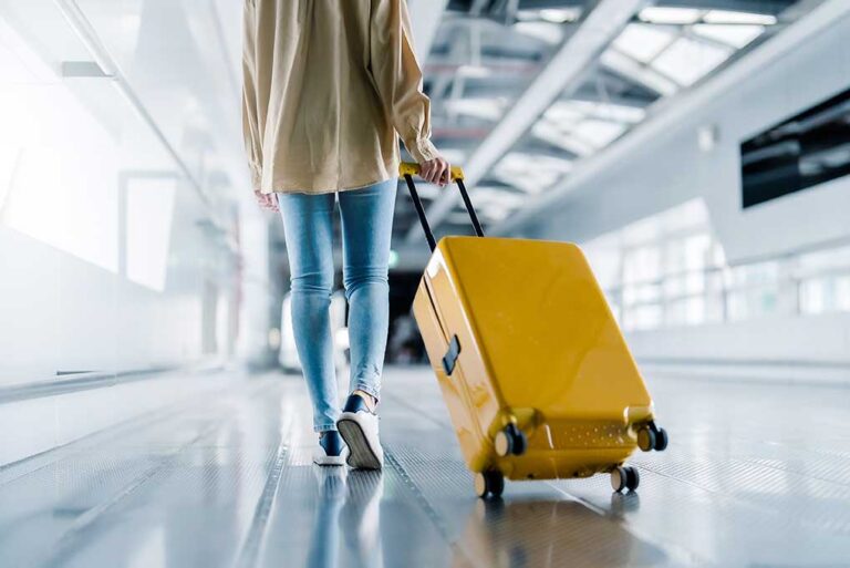 A shot, taken from behind, of a young woman walking in an airport terminal.