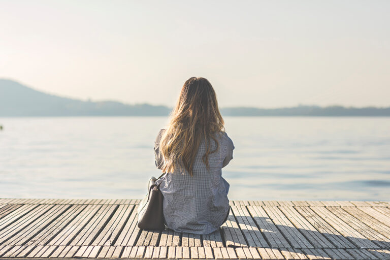Woman sitting on dock in front of lake