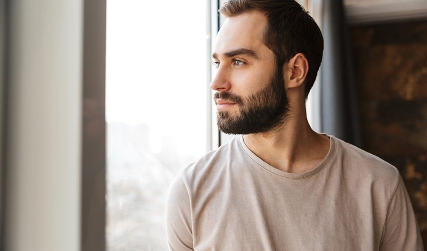 shutterstock_1674151522 Young man staring out the window